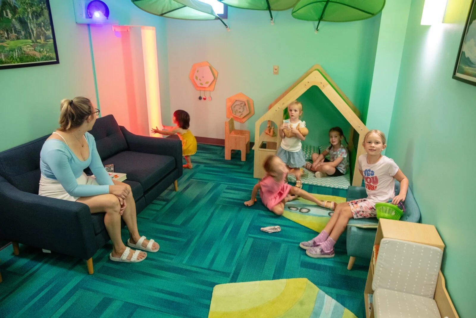 A calm sensory-friendly room with soft lighting and a play house